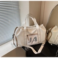 Detail of a cream nylon travel bag with brown trim and adjustable shoulder strap - Off-white