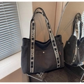 Detail of black canvas tote bag featuring embroidered floral shoulder strap and side pocket - Black
