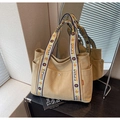 Detail of canvas tote bag showing wide woven shoulder strap and metal buckle on the pocket - Khaki