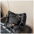 Detail of glossy black shoulder bag featuring a decorative bow and silver chain strap - Black