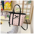 Detail of pink bubble texture tote bag with black bow and heart pendant in hand - Pink