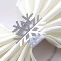 Detalle de un servilletero de copo de nieve plateado sobre una servilleta de satén blanco - Plata Espejo