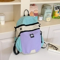 Detail of color-block nylon backpack featuring blue and beige panels in lifestyle setting - Blue