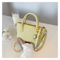 Pale yellow litchi grain tote bag with heart charm and woven rope handle detail - Yellow