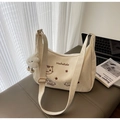 Cream canvas tote bag with cat embroidery and cloud charm on a leather bench - Off-white