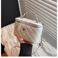 White quilted bucket bag with chain strap and silver floral charm detail in hand - White