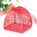 Close-up of red laser-cut wedding favor box with rose patterns and a silk ribbon bow - Pearlescent Red