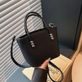 Black bucket bag with lychee texture and silver bead details held by hand - Black