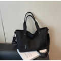 Detail of black canvas tote bag showing side pockets, woven label and adjustable wide strap - Black