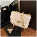 Macro shot of white quilted flap crossbody bag with gold metal lock and chain strap - White