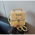 Détail du sac à dos jaune en cuir avec boucle papillon et décoration de franges perlées - Jaune