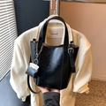 Fashionable black faux leather bucket bag with shiny crinkled texture and mini pouch charm - Black