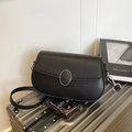 Minimalist black crossbody saddle bag with oval buckle on a silver suitcase - Black