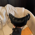 Black vegan leather croissant bag featuring vertical stitching and knotted tassel detail - Black