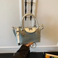 Blue denim handbag with silver studs and bow buckle shown in hand - Light Blue Without Pendant