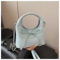 Detailed view of light blue leather handbag featuring bow decoration and silver metal chain - Blue