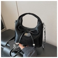 Detail of black patent leather bag with bow accent and TAYOR STORIES metal logo plate - Black