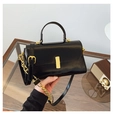 Detail of black glossy leather handbag with gold metal clasp and dual shoulder straps - Black