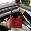 Elegant red leather bucket bag with decorative bow tie and metallic beads in car interior - Red