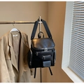 Detail view of a black multi-pocket PU leather backpack on a metal hanger - Black