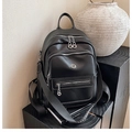 Detail of black leather backpack featuring contrast white stitching and metal logo on the base - Black