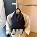 Black versatile nylon backpack and handbag with metallic buckle shown in hanging view - Black