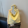 Light yellow casual tote bag with pleated handle and pink drawstring accent on art book - Yellow