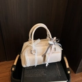 Schicke cremefarbene Bowling-Handtasche mit Spitze und Schleifen auf Holzuntergrund - Gebrochenes Weiß
