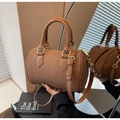 Detail of a brown cylindrical Boston bag with leather trim and gold-tone hardware finish - Mocha Brown