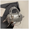 Dettaglio di una borsa Boston argento opaco con ciondolo a cuore accanto a un blazer - Argento (Con Ciondolo)