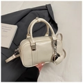Detail of a cream Boston bag with heart charm and silver chain on a gray blazer - White with Pendant