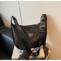 Detailed close-up of a black nylon crescent bag with wide canvas strap and brand plate - Black (Textured)