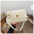 Détail du sac bandoulière en cuir blanc crème avec boucle dorée et breloque tressée - Blanc Cassé