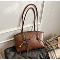 Detailed shot of dark brown faux leather tote with braided knot charm and fine texture - With Charm / Brown