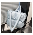Macro shot of light blue quilted tote bag featuring padded grid texture and soft thick handles - Blue