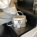 Schicke silberne Metallic-Beuteltasche mit Rundgriff und Schultergurt auf einer Treppe - Silber
