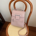 Pink minimalist tote bag with metal chain and ball pendant on a woven designer chair - Pink