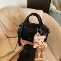 Black pebble leather bowling bag with cute teddy bear charm on beige sofa background - Black (With Pendant)