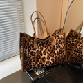 Leopard print tote bag with brown handles and fuzzy texture on a stack of books - Brown