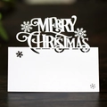 Tarjeta de Navidad blanca cortada con láser con copos sobre fondo de madera - Blanco