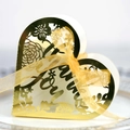 Macro view of gold heart-shaped laser cut wedding favor box with Love text and ribbon - Reflective Gold