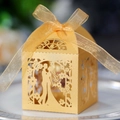 Macro shot of laser-cut gold wedding favor box featuring bride and groom silhouette - Gold