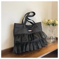 Dettaglio borsa tote in denim nero con volant in organza e etichetta alla moda - Nero