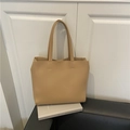 Minimalist beige faux leather tote bag with long shoulder straps on a black sofa - Brown