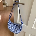 Detail view of the blue and white checkered canvas crescent bag with a striped shoulder strap - Blue