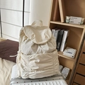 Creamy white nylon drawstring backpack with a large front pocket on a white suitcase - White