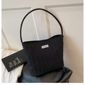 Detailed view of black quilted canvas shoulder bag featuring a circular leather handle - Black