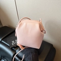 Bolso bandolera tipo cubo en rosa de piel granulada sostenido por una modelo - Rosa