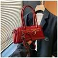 Detailed close-up of a vintage red glossy leather handbag with silver hardware and buckles - With Pendant Style / Red