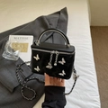 Black box bag with silver bow charms and metallic handle shown in a lifestyle setting - Black
